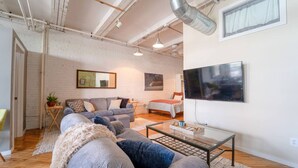Een moderne woonkamer met een bank, een salontafel en een bed op de achtergrond.