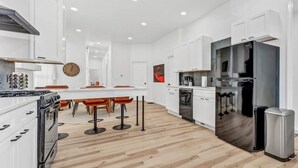 A modern kitchen with white cabinets, a stainless steel refrigerator, and a wooden floor. - Two Level Apt: Dtwn Buffalo (Buffalo)