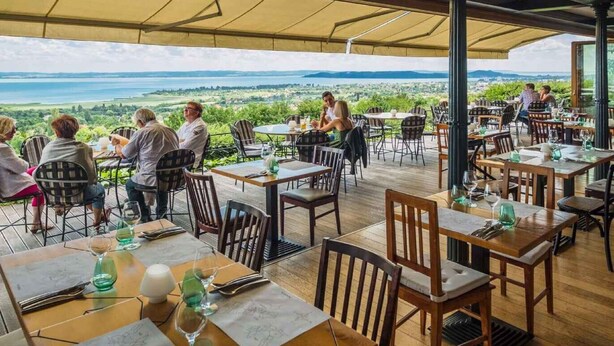 An outdoor dining area with tables and chairs, overlooking a scenic landscape. - Studio with large terrace and mountain view (Csopak)