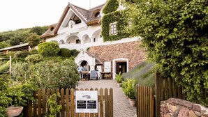 A rustic building with a stone facade, arched windows, and a wooden fence. - Studio with large terrace and mountain view (Csopak)