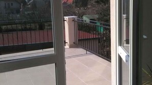 A balcony with a view of houses and trees, a tiled floor, and a metal railing. - Studio with large terrace and mountain view (Csopak)