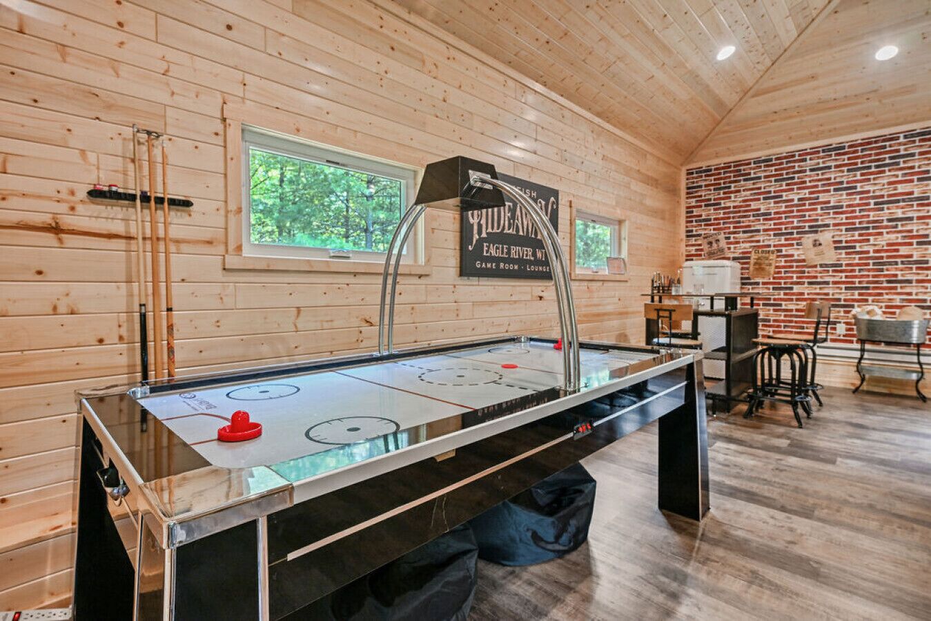 Ein Holzkaminzimmer mit einer Shuffleboard-Spielfläche, Fenstern und einer Ziegelwand.