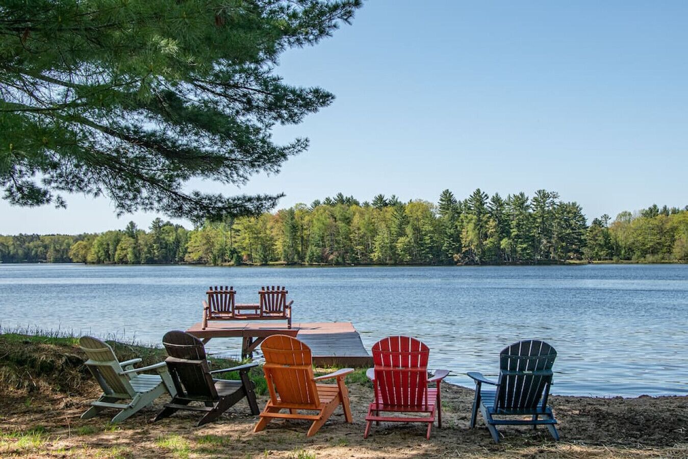 A lakeside seating area with a table and chairs, surrounded by trees and water.