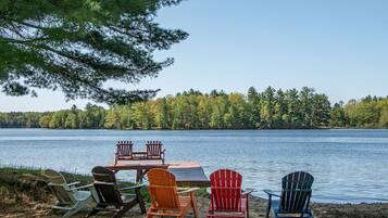 A lakeside seating area with a table and chairs, surrounded by trees and water.