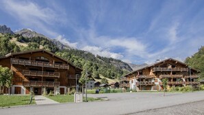 Un chalet de madera con balcones, con montañas al fondo.