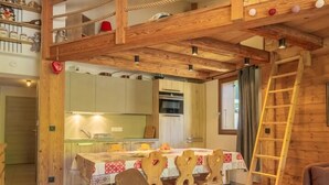 Un interior rústico de madera con comedor, habitación en entrepiso y cocina.