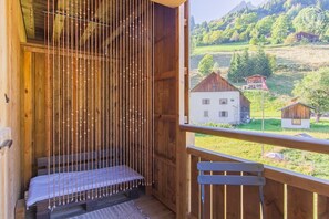A wooden balcony with a bench and a view of a rural landscape including houses and greenery. - LES Marmottes - LA Giettaz (LA GIETTAZ)