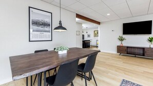 A modern dining area with a wooden table, black chairs, a pendant light, and a framed picture on the wall. - Creekside Getaway: On the Creek in Anchorage (Anchorage)