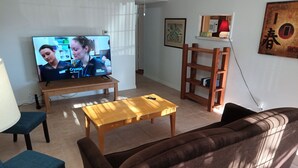 A living room with a TV, wooden furniture, a sofa, and a coffee table. - Comfortable for travelers tired of staying at hotels. (Kingman)