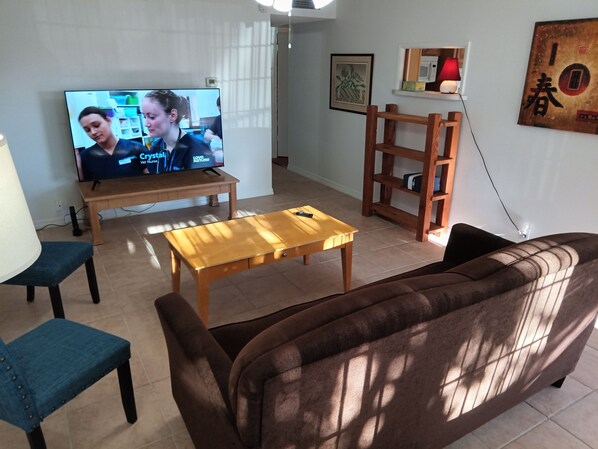A living room with a TV, wooden furniture, a sofa, and a coffee table.