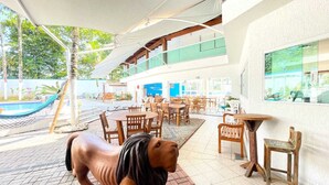 Uma área à beira da piscina com mobiliário de exterior e uma rede.