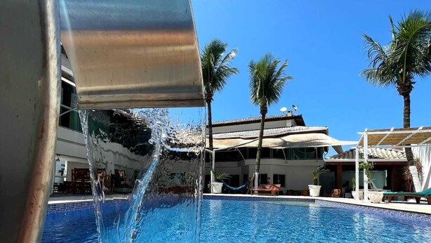 Visão clara de uma piscina com água sendo despejada de um recipiente metálico.