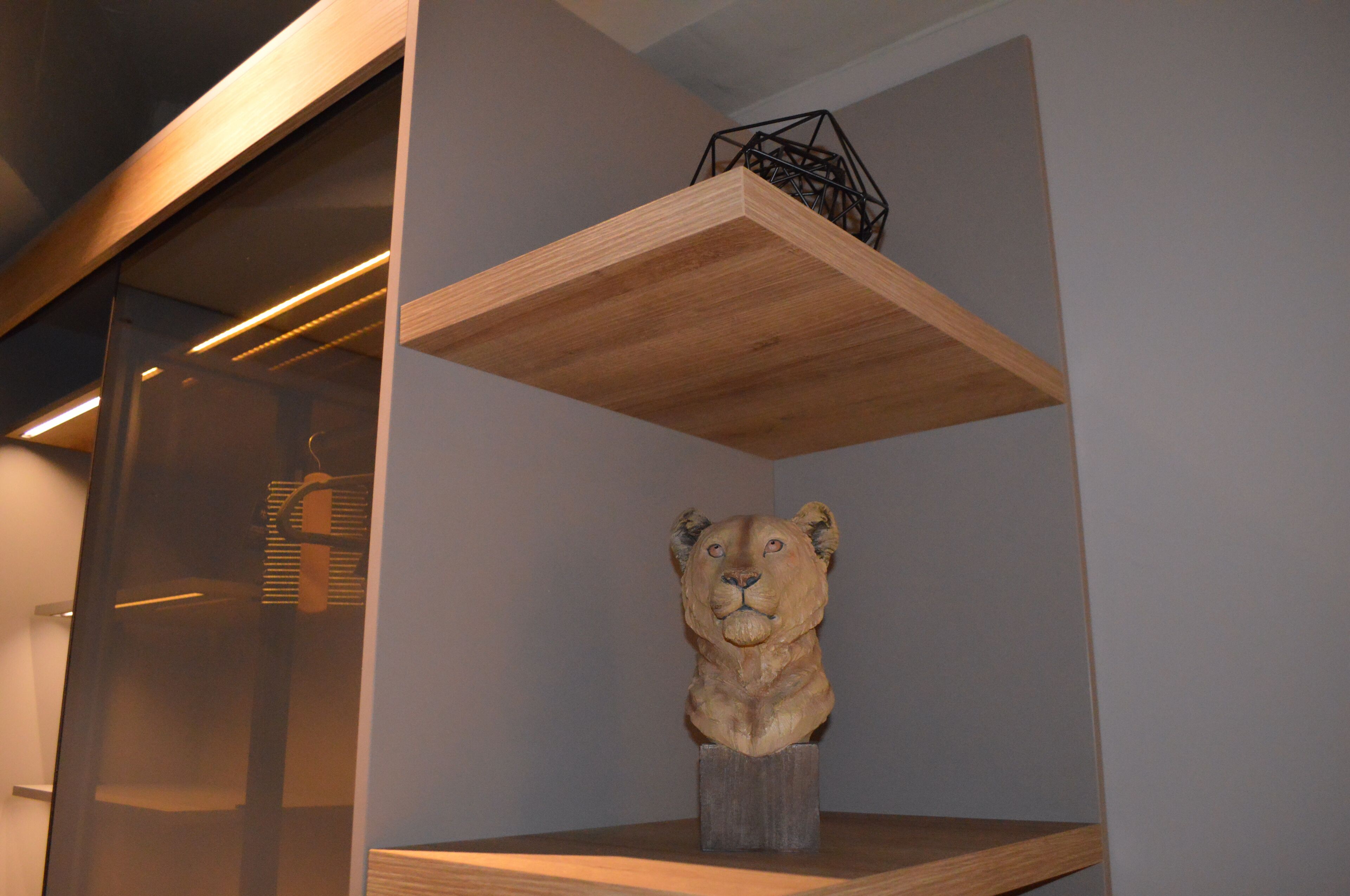 A wooden shelf with a lion sculpture in a room with a modern design.