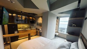 A modern hotel room with a large bed, a kitchenette, a small dining area, and a view of the city. - Luxury Smart Loft in Bogota Chico , GYM POOL AND SPA  (Bogotá)