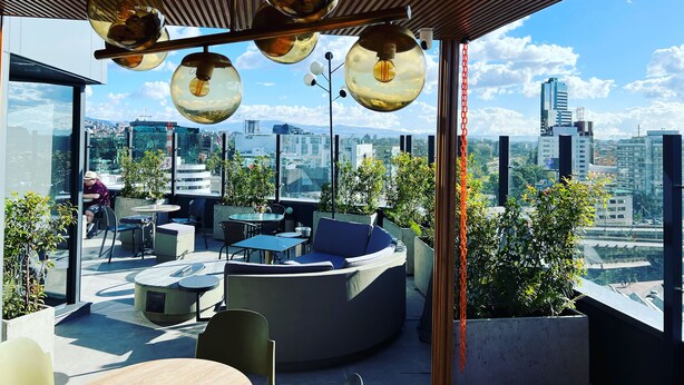 A rooftop terrace with modern seating, a view of the cityscape, and hanging spherical light fixtures. - Luxury Smart Loft in Bogota Chico , GYM POOL AND SPA  (Bogotá)