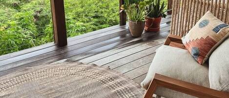 A balcony with a view of the sea, wooden furniture, and potted plants.