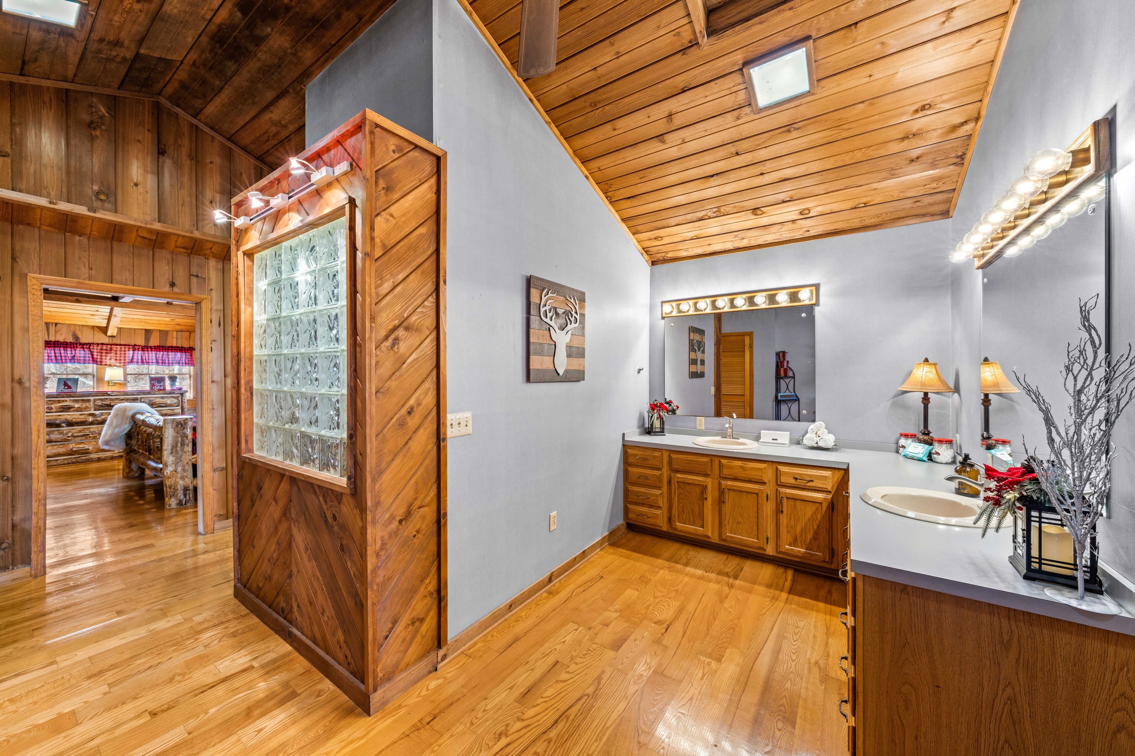 A bathroom with wooden flooring, a vanity with a mirror, and a sink.