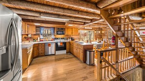 Una cocina amplia con armarios de madera, un refrigerador de acero inoxidable y una escalera de madera.