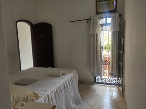 A bedroom with a bed, a wardrobe, a window with curtains, and a door leading outside.