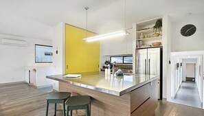 A modern kitchen with a central island, white cabinetry, and a yellow accent wall.