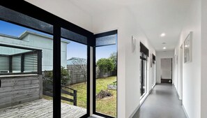 A modern interior with a wooden deck, a glass door leading outside, and a hallway with framed pictures.