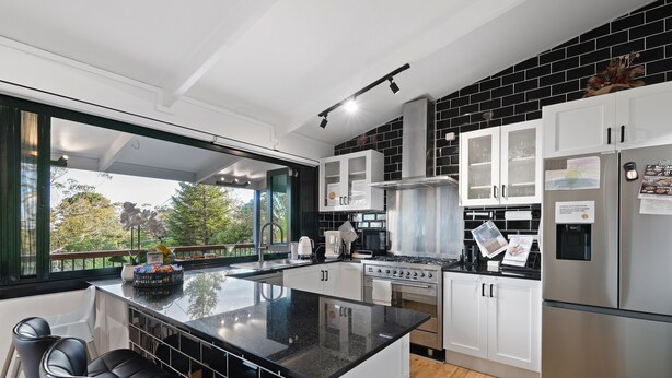 A modern kitchen with a large island, stainless steel appliances, and a view of the outdoors.