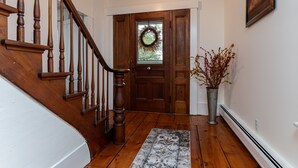 A wooden staircase leading to a door with a wreath, a potted plant, and a framed picture on the wall. - Historic 150-year-old farmhouse, Jacuzzi included (Chester)