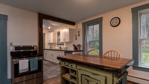 A kitchen with a wooden island, stainless steel appliances, and a view of the outdoors through a window. - Historic 150-year-old farmhouse, Jacuzzi included (Chester)