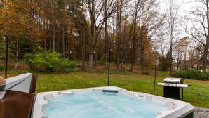 A hot tub in a forested area with a grill and a sign. - Historic 150-year-old farmhouse, Jacuzzi included (Chester)