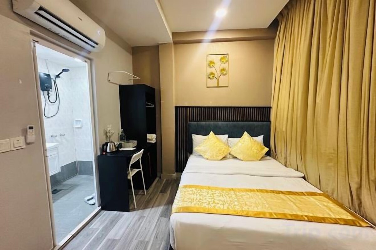 A hotel room with a bed, a desk, a chair, a shower, and a wardrobe.
