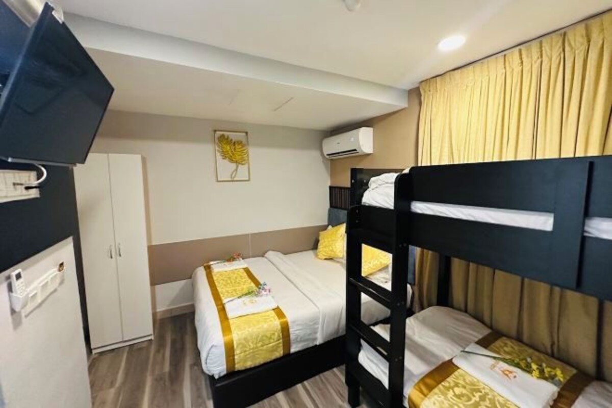 A hotel room with bunk beds, a wardrobe, a flat-screen TV, and an air conditioning unit.