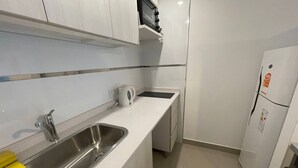 A modern kitchen with a stainless steel sink, a kettle, and a white refrigerator. - Urban Luxury- Studio Living in San Telmo Num4649 (Buenos Aires)