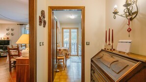 A hallway with a wooden cabinet, a dining area with a table and chairs, and a decorative wall piece. - Lovely apartment for 5 guests with WIFI, TV and balcony (Canazei)