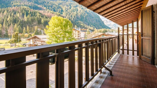 A wooden balcony with a view of a forested mountain range. - Lovely apartment for 5 guests with WIFI, TV and balcony (Canazei)
