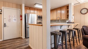 Una cocina moderna con armarios de madera, electrodomésticos de acero inoxidable y una zona de bar con taburetes.