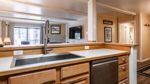 Una cocina moderna con armarios de madera, un lavamanos de acero inoxidable y un lavavajillas empotrado.