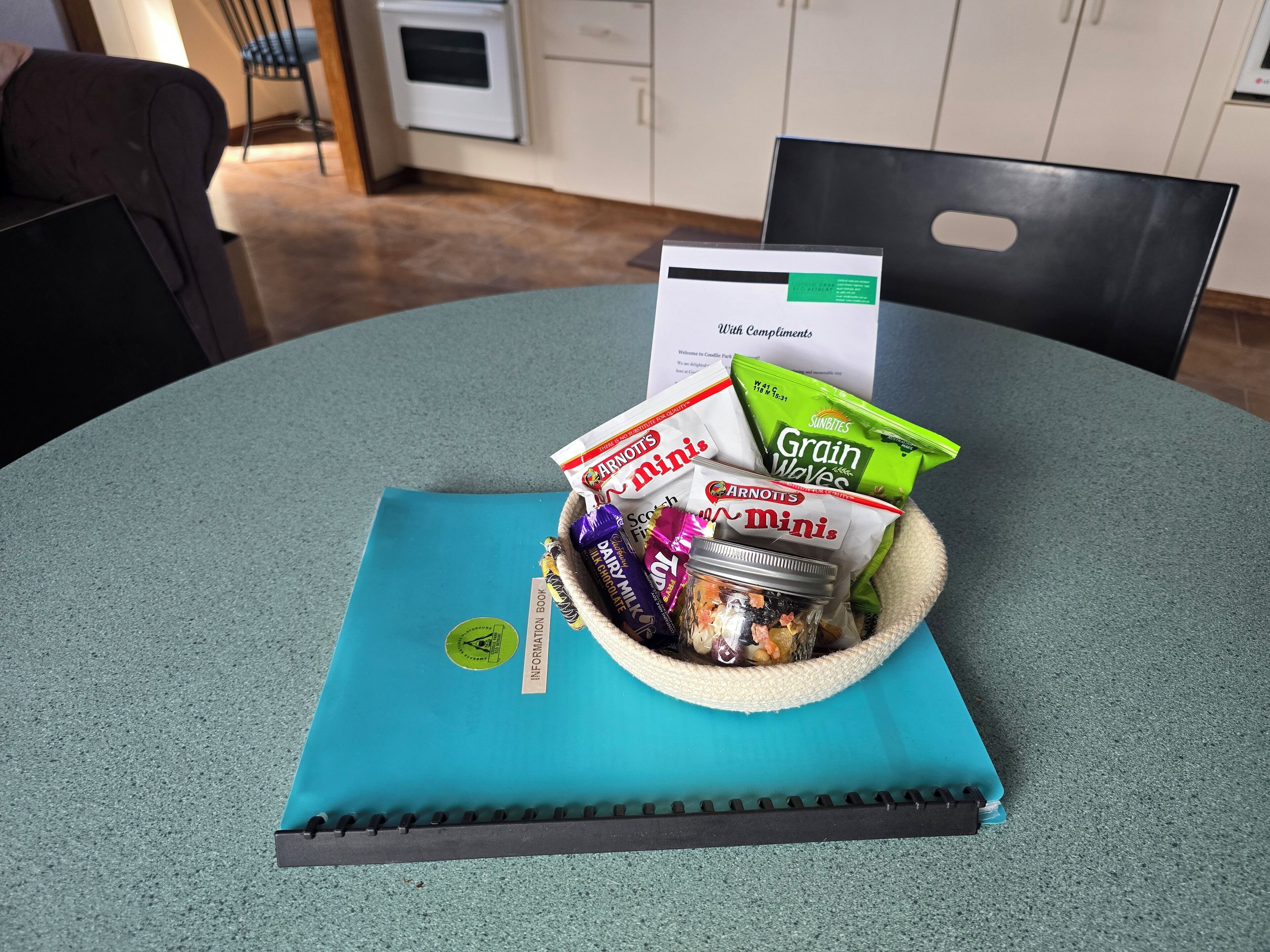 A table with a basket containing snacks, a book, and a card.