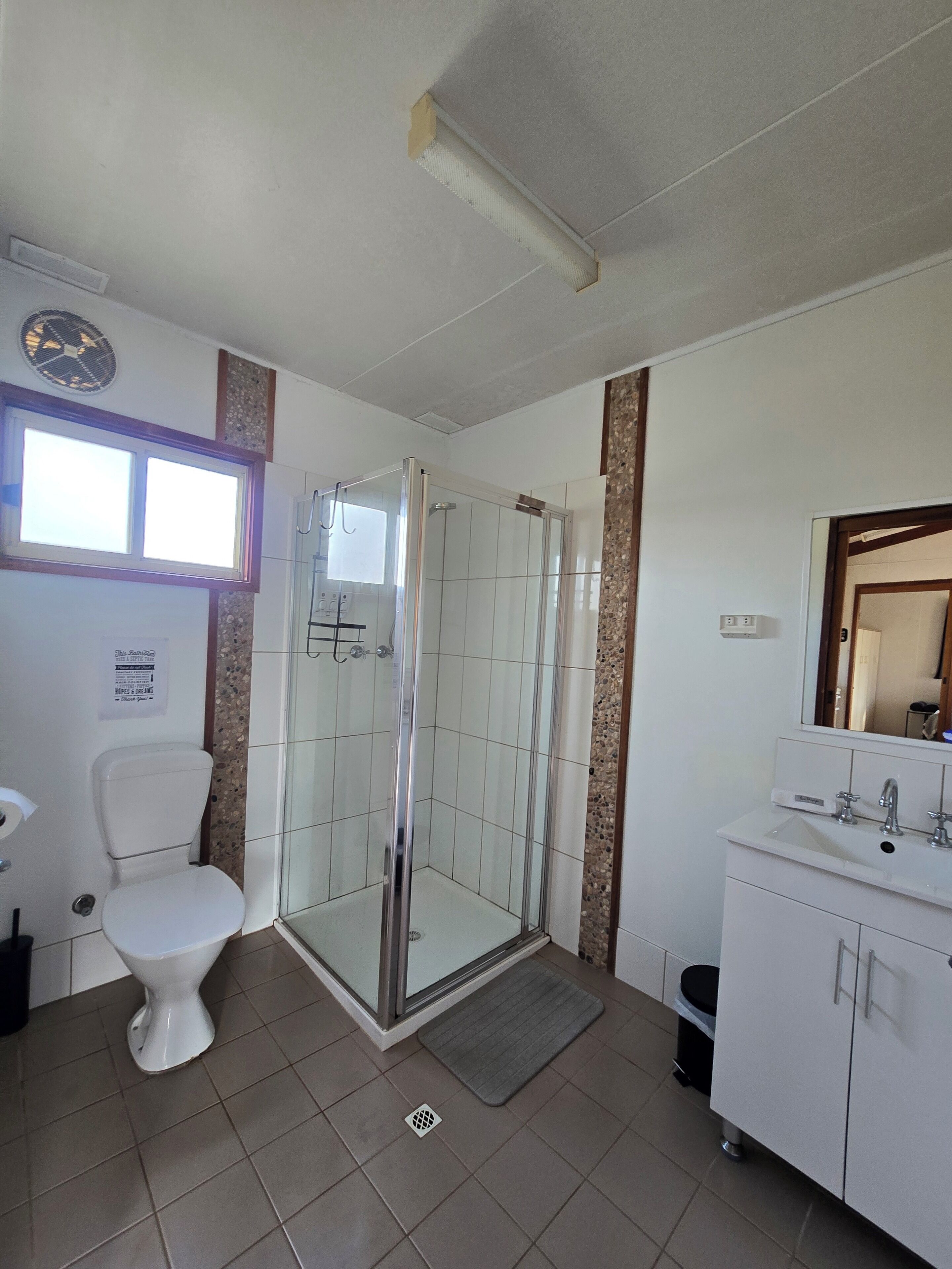 Een badkamer met toilet, een douchecabine, een wastafel en een spiegel.