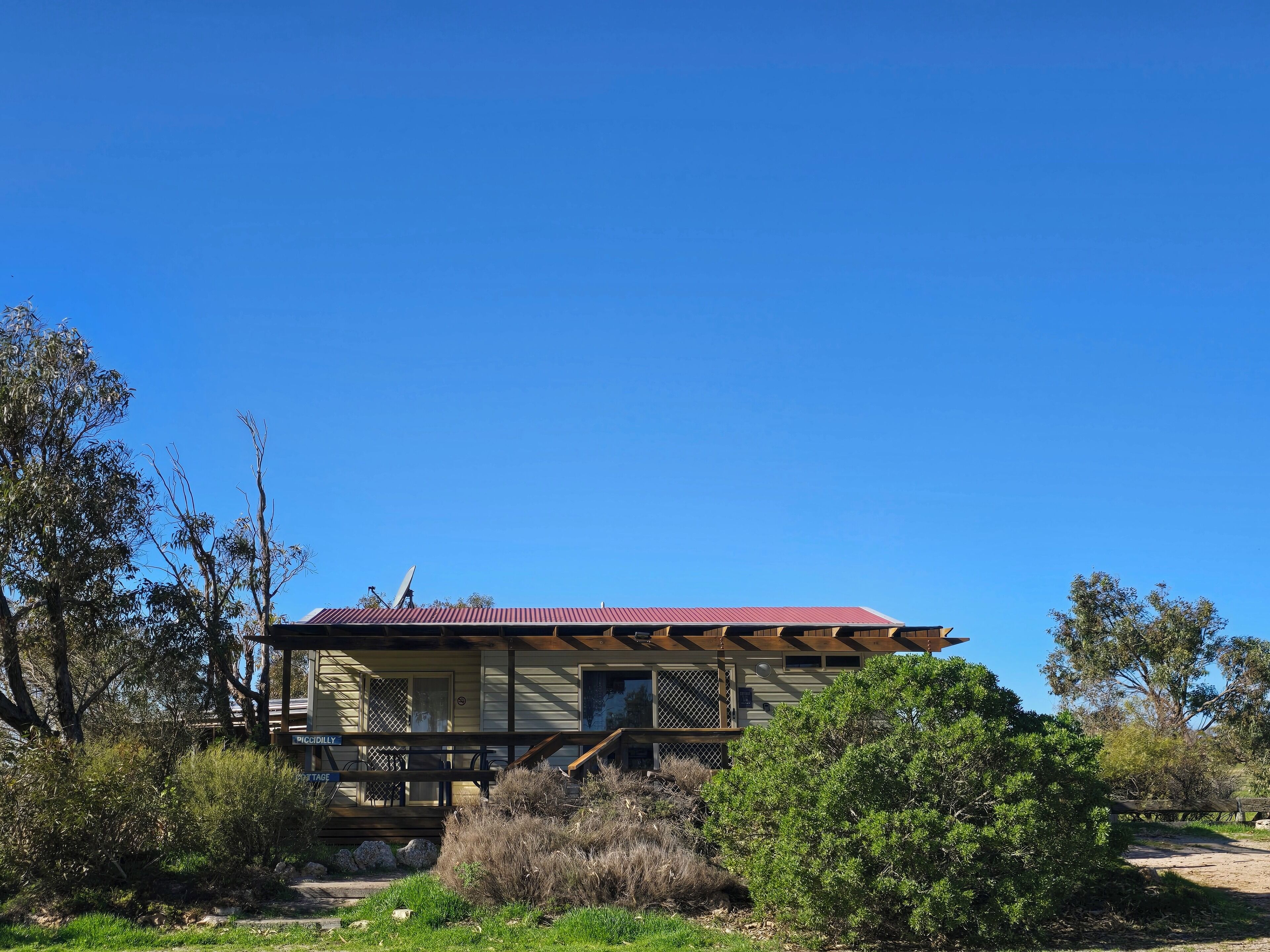 A two-story house with a red roof, a porch with a railing, and a satellite dish.