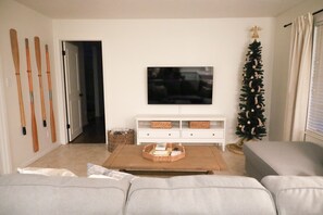 A living room with a television, a Christmas tree, and a sofa.
