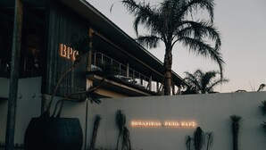 A building with a large planter and a neon sign reading "BOTANICAL POOL CLUB."
