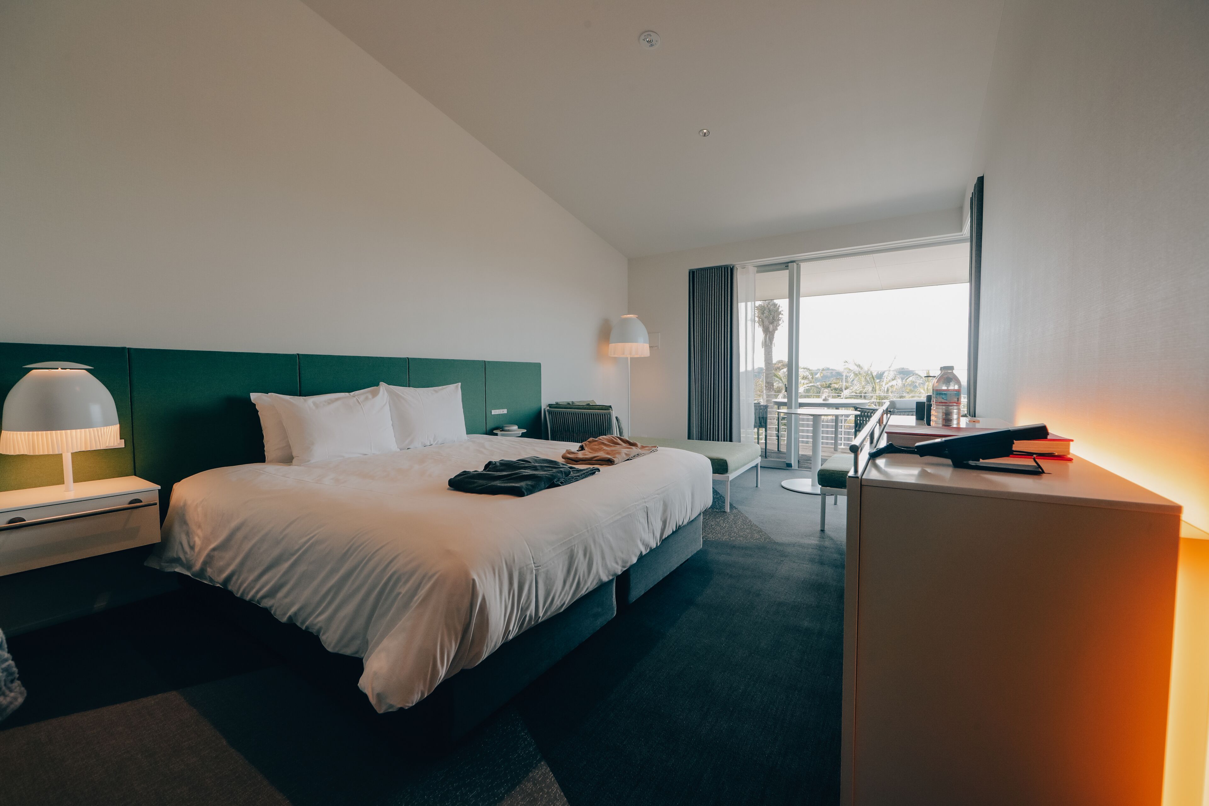 Hotellihuone, jossa on suuri sänky, työpöytä, tuoli, lamppu ja näkymä kaupunkiin.
