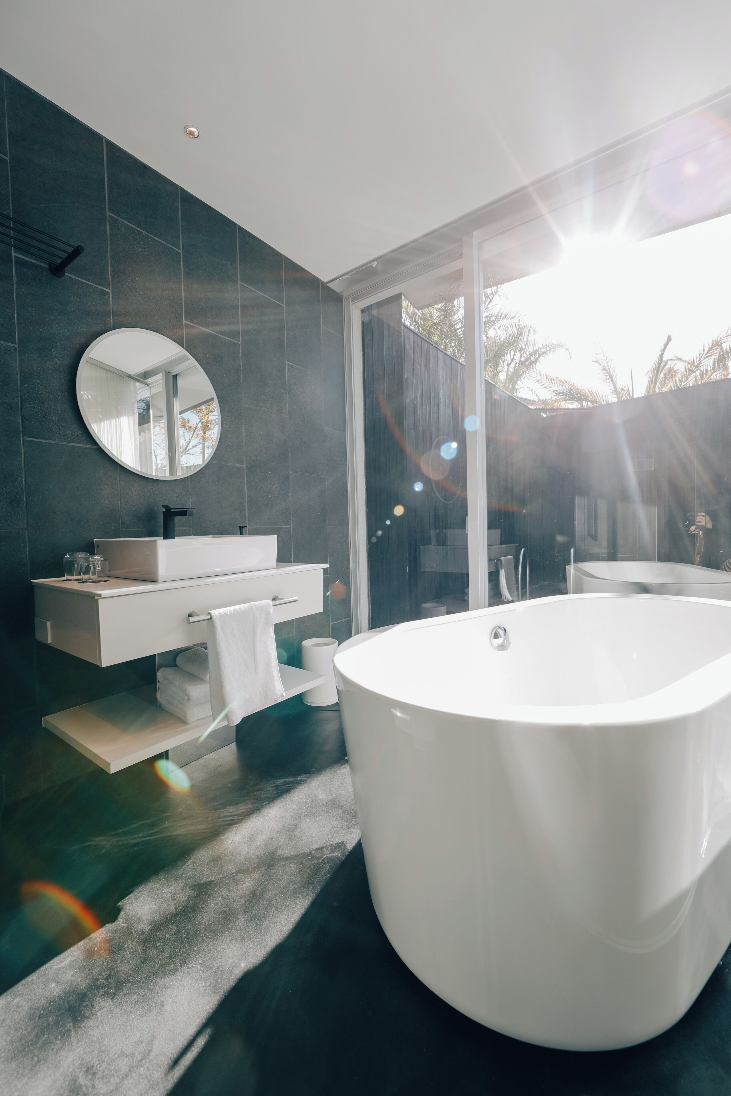 A modern bathroom with a freestanding bathtub, a vanity with a mirror, and a glass shower enclosure.