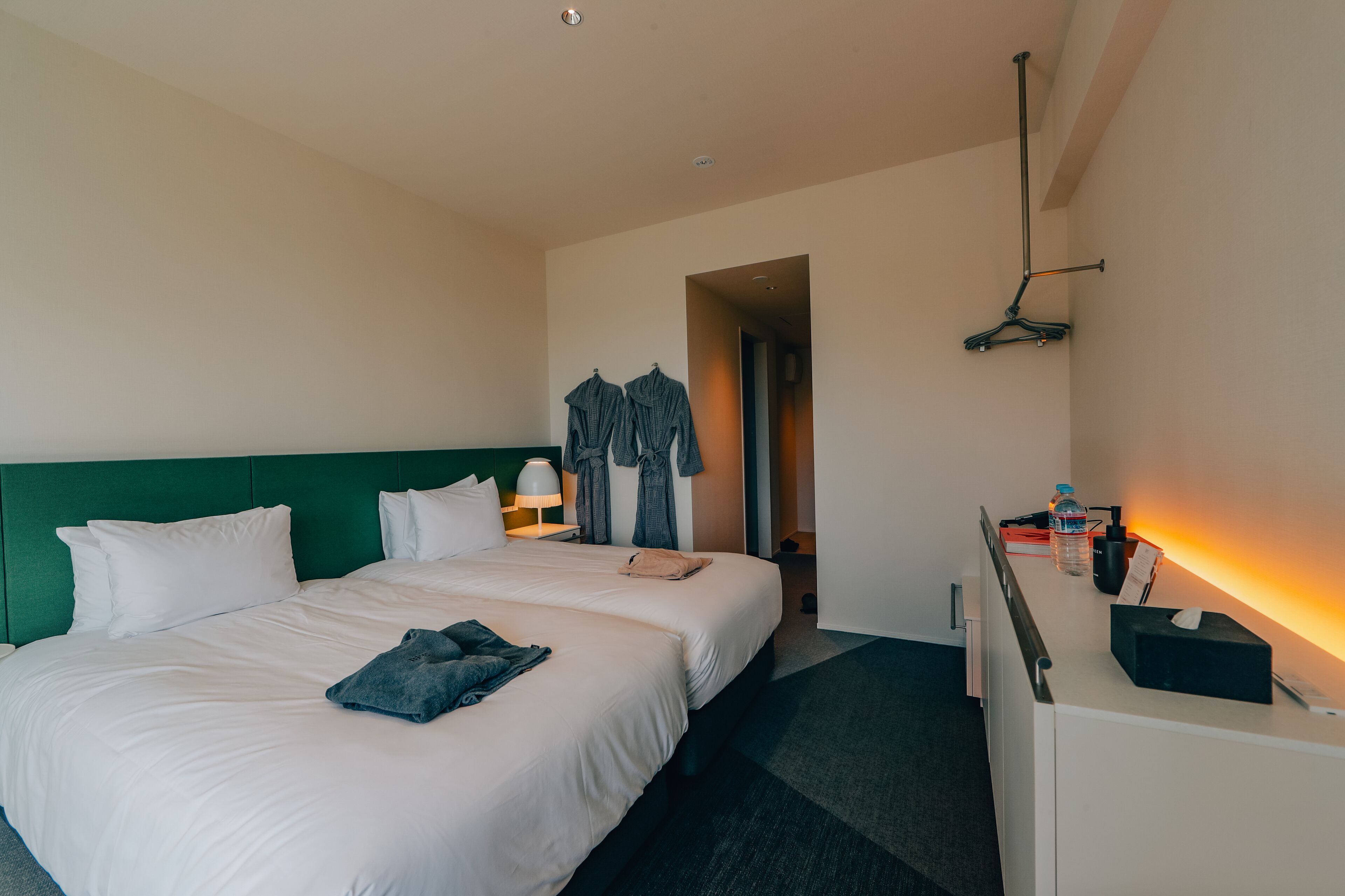 Ein Hotelzimmer mit einem großen Bett, einem Schreibtisch mit Lampe und einem Kleiderständer.