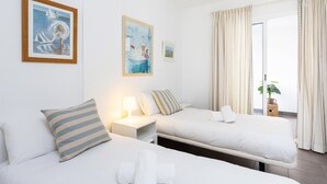 Et hotelværelse med to senge, et natbord med lampe og et vindue med gardiner.