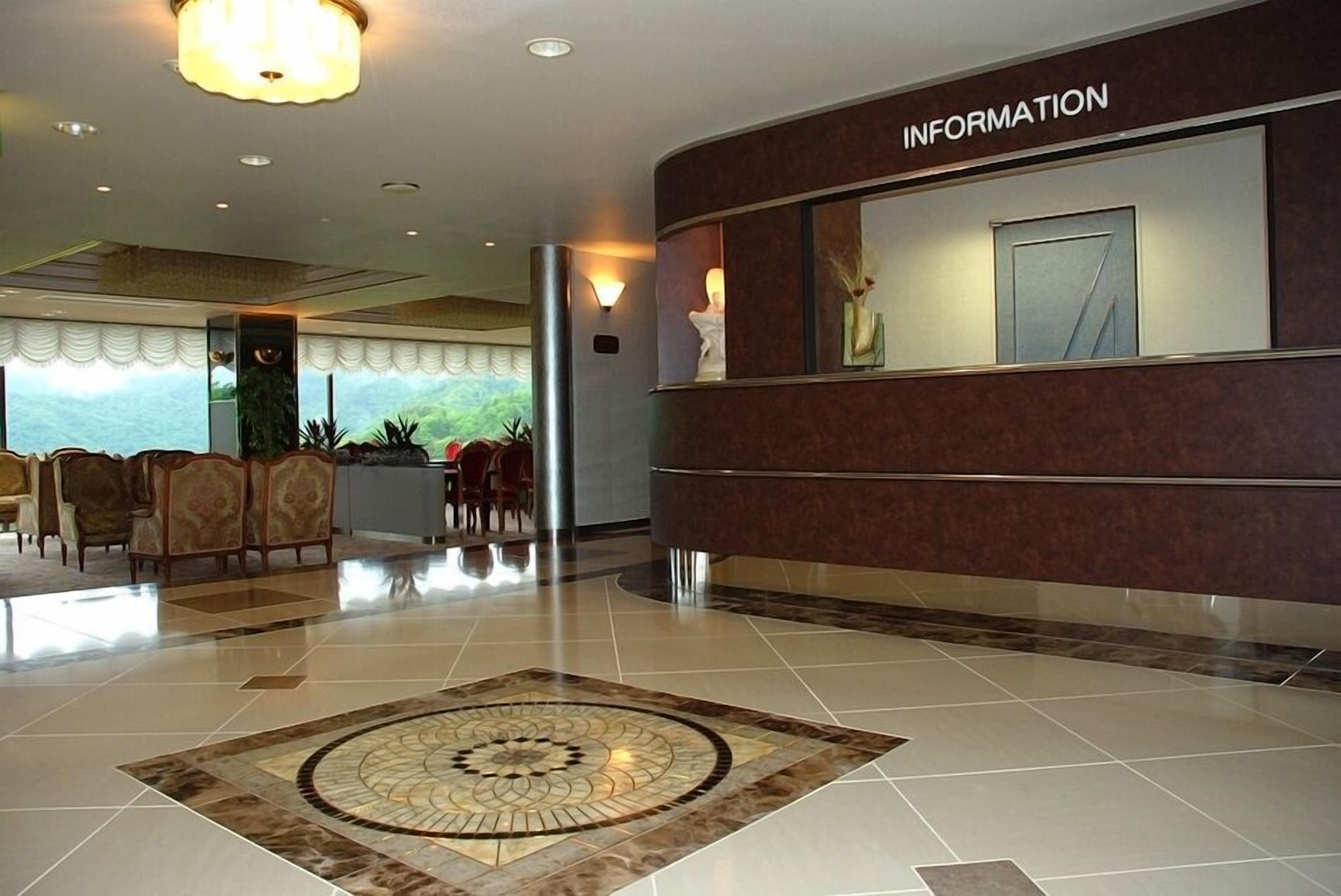 A lobby with a reception desk labeled 'INFORMATION,' a patterned carpet, and a seating area with chairs.