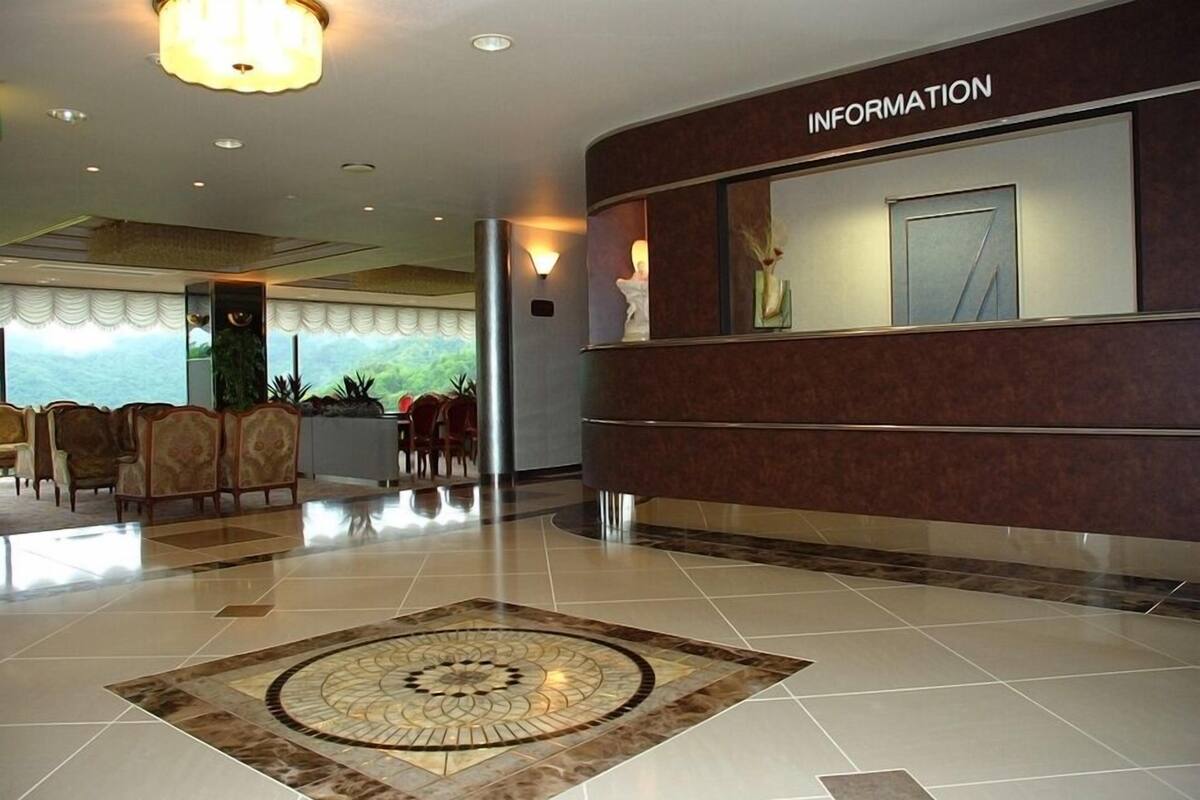 A lobby with a reception desk labeled 'INFORMATION,' a patterned carpet, and a seating area with chairs.
