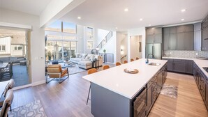 A spacious kitchen with a large island, grey cabinets, and a modern design.