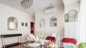 A modern dining area with a glass table, red chairs, and a chandelier. - Pure Seville elegance and comfort (Sevilla)