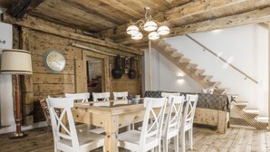 Un comedor de madera con una mesa y sillas, un reloj y una escalera al fondo.